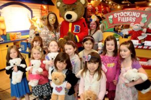 girls holding bears standing with bear mascot